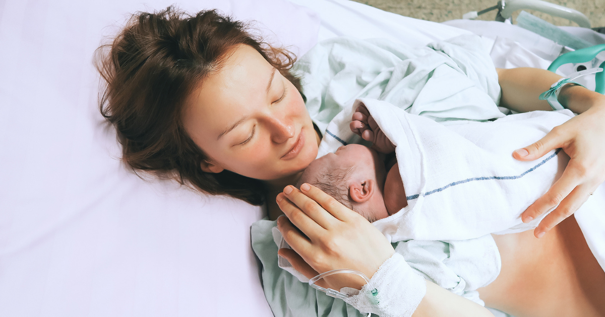New mother holds baby in hospital bed